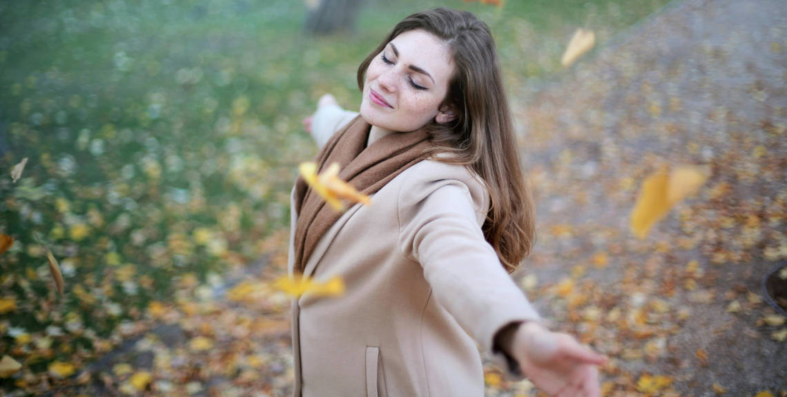 Frau steht glücklich auf Herbstwiese